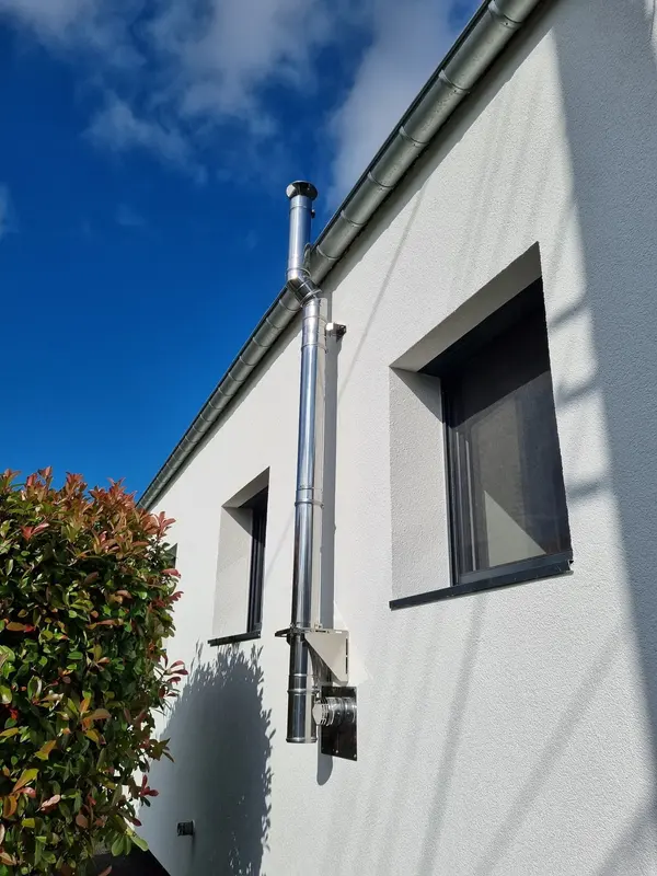 Conduit de fumée double paroi inox fixé en façade d'une maison blanche