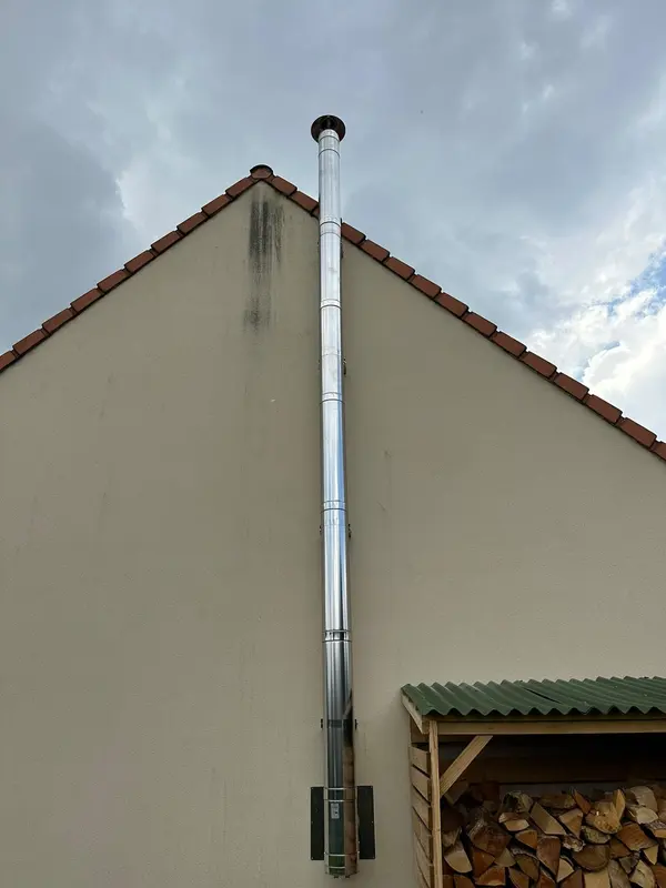 Conduit inox double paroi montant le long du pignon d'une maison jusqu'au-dessus du faîtage