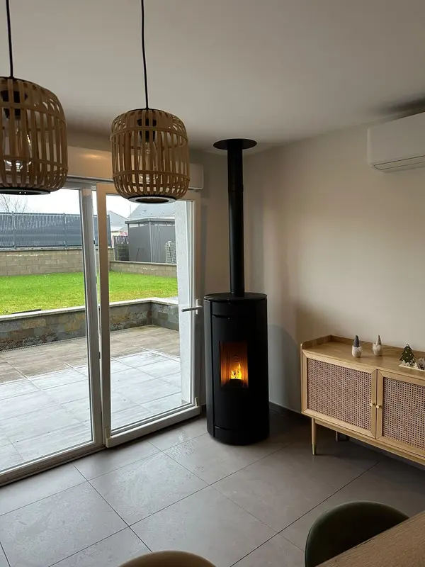 Poêle à granulés noir avec conduit vertical dans un séjour lumineux ouvert sur la terrasse