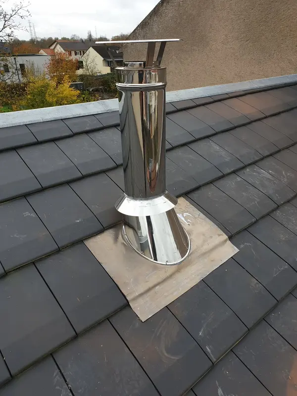 Sortie de toit en inox avec solin d'étanchéité sur une toiture en ardoise