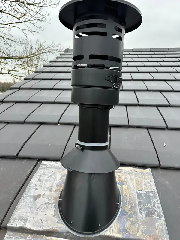 Sortie de toit noire avec chapeau et solin sur une toiture en tuiles plates
